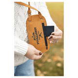 Close-up of a person wearing a tan custom phone bag, pulling a black card from the side zipper pocket.