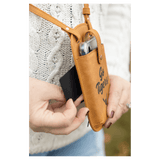 Hands pull a card from a brown crossbody phone bag printed with 