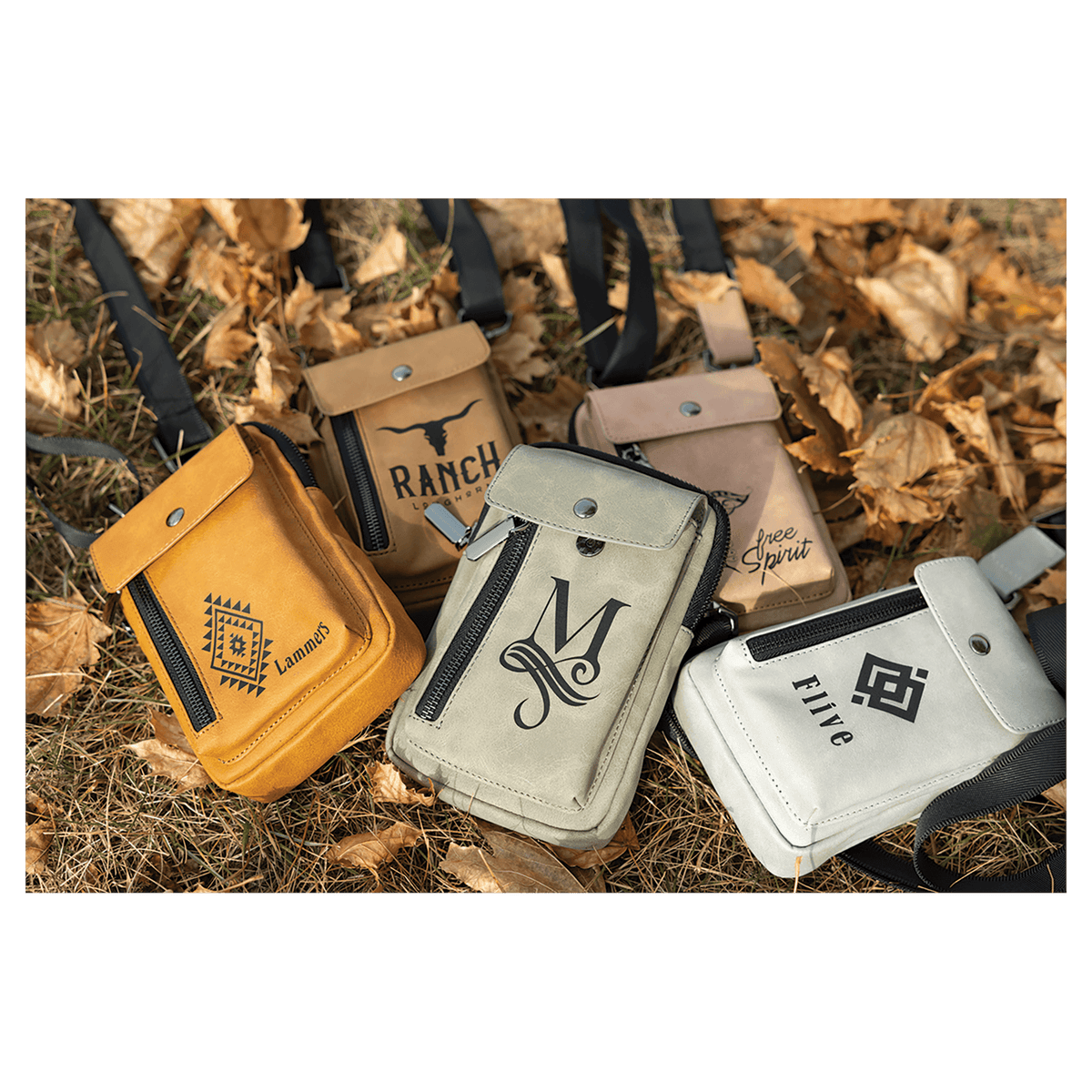 Four crossbody bags in yellow, tan, grey, and white with black graphics, resting outdoors on dry autumn leaves.