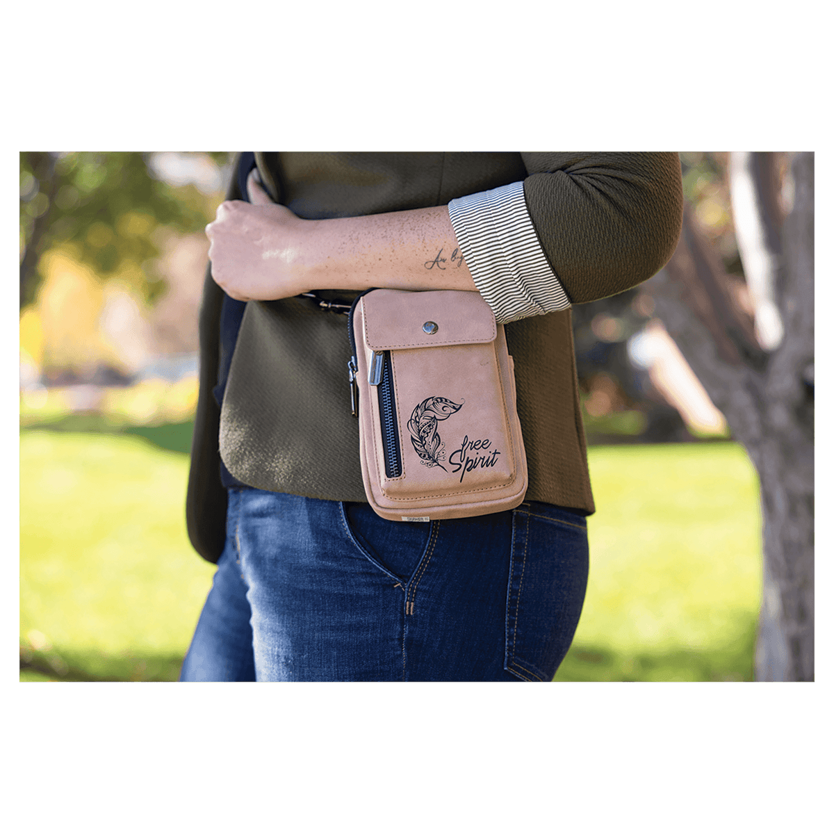 Pink bag with flap pocket, snap hardware, and side zipper worn at the hip by a person outdoors in a green park.