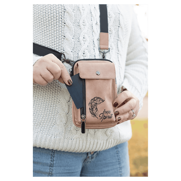 Person outdoors wearing a pink crossbody bag with black strap, metal clips, and side zipper, pulling out a card.
